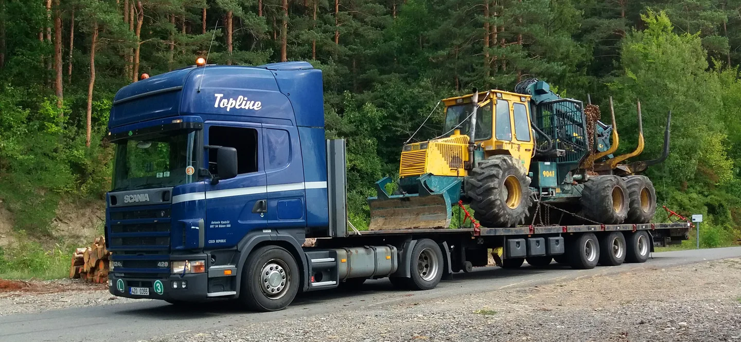 Modrá Scania Antonína Vystrčila s lesnickým strojem na podvalníku